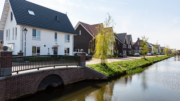 Scenic canal-side residential area in Het Gooi, Netherlands, featuring charming houses and lush greenery, ideal for expat families in Netherland seeking a tranquil lifestyle.